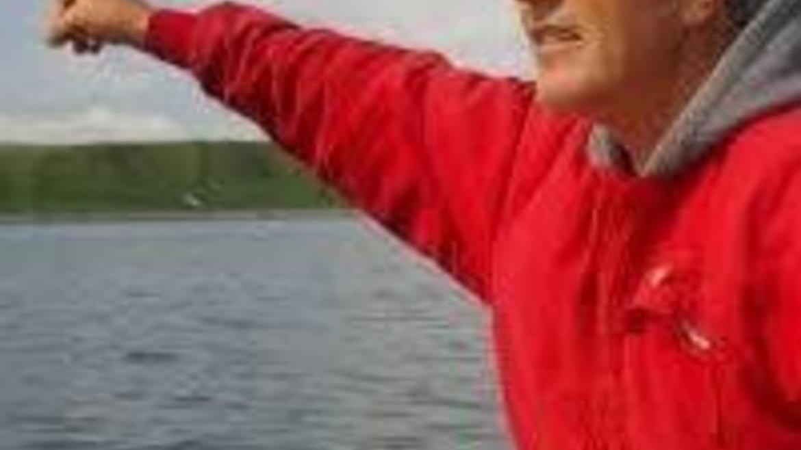 man by lake, pointing