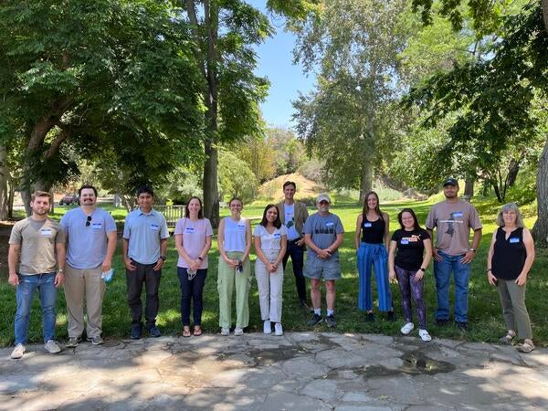 12 people standing in grass under trees